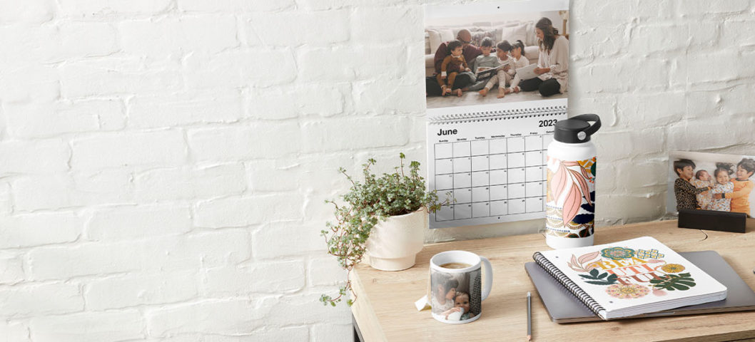 2023 wall calendar posted on a white brick wall in front of a desk full of personalized shutterfly items