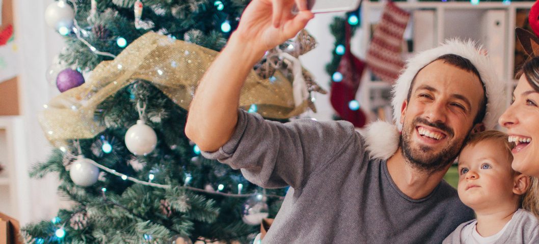 family taking a selfie in front of the christmas tree.