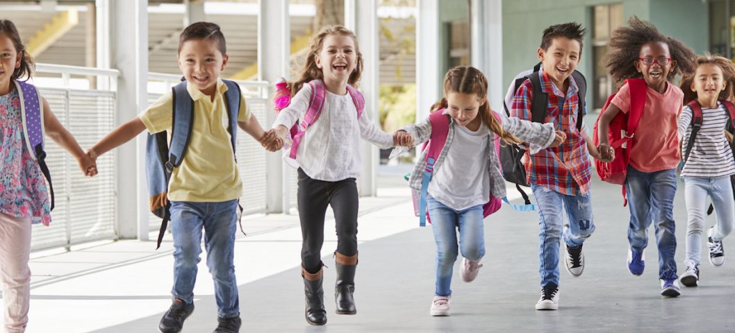 Primary school kids run holding hands in corridor with school quotes overlay.